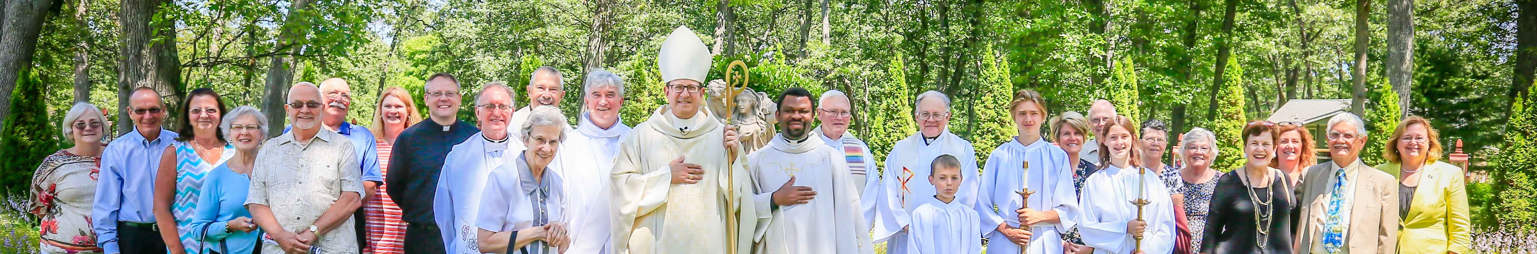 bishop walkowiak poses with fr. godfrey onyekwere and parishioners of st. mary of the woods in muskegon