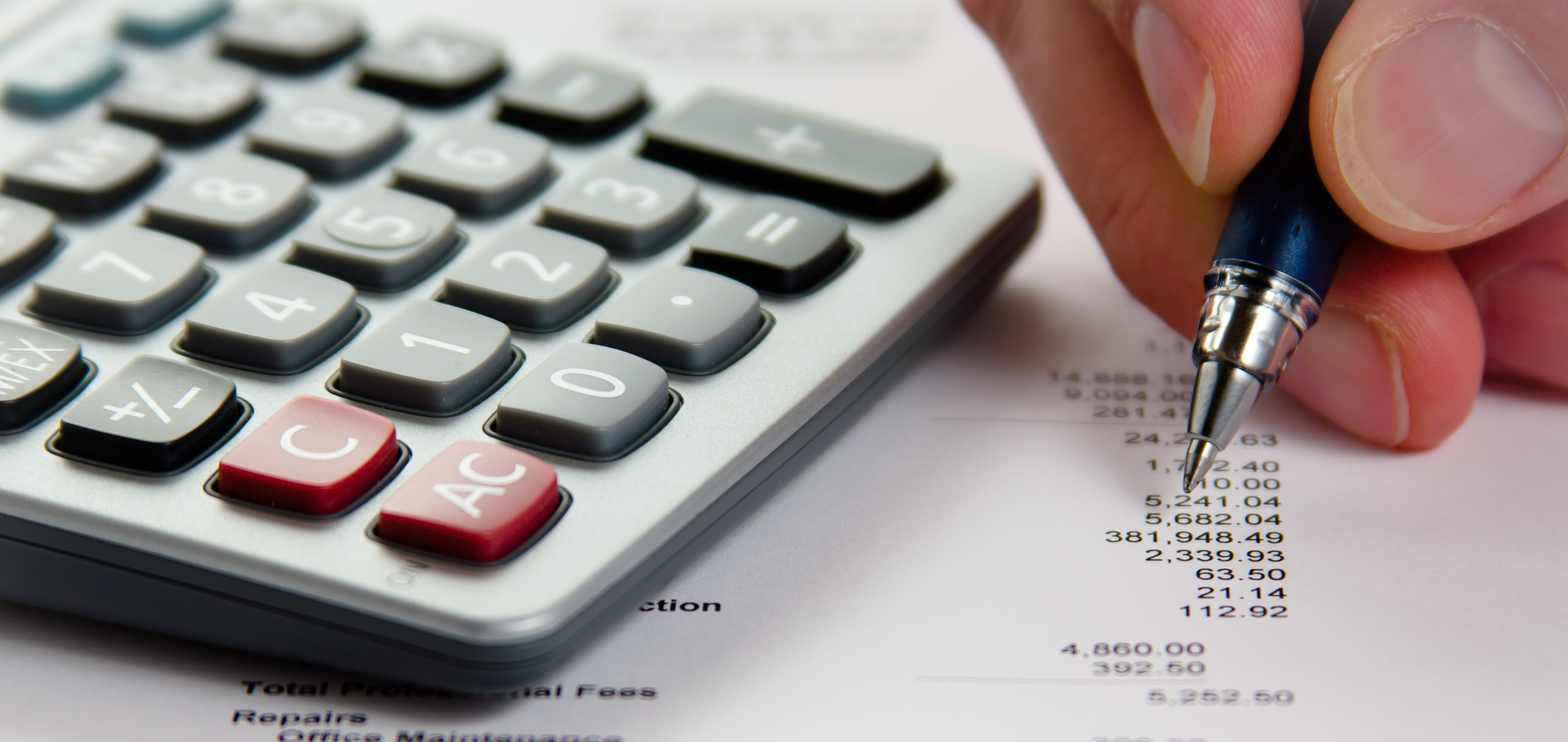 Hand holding a pen reviewing numbers on a spreadsheet