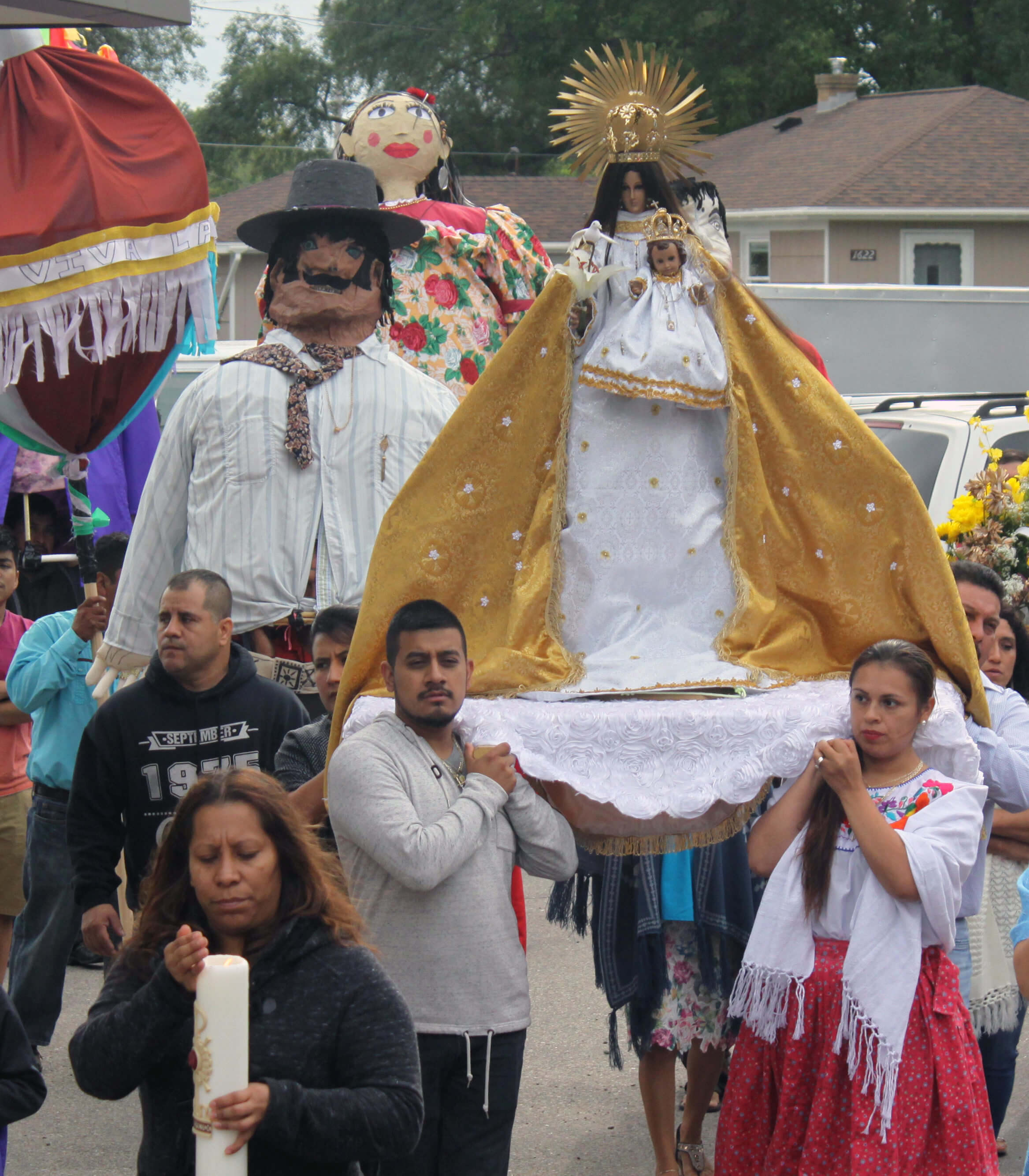a crowd of hispanic catholics carry a statue of the virgin mary in a procession to mark the nativity of her birth outside holy name of jesus parish in wyoming, michigan