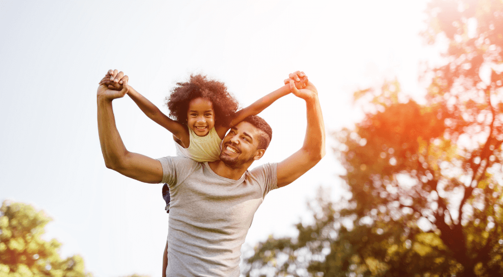 Image of a father hoisting his daughter onto his shoulders