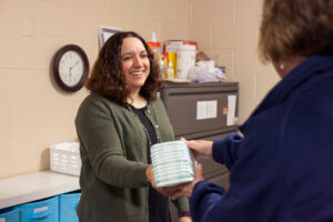 Michele Misiak hands a volunteer a stack of disposable diapers
