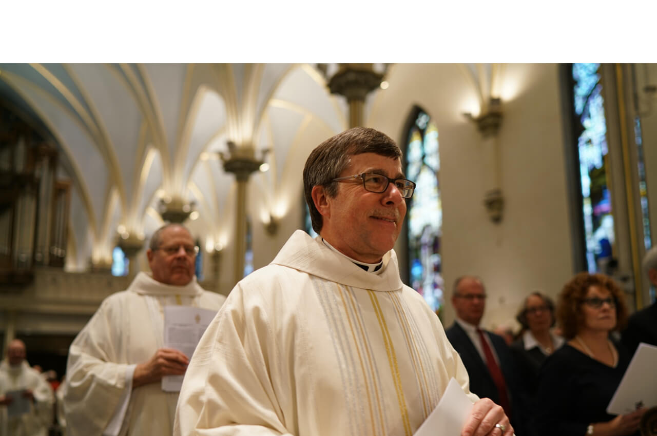 Father Mark Peacock processes into the Cathedral of Saint Andrew, no logo