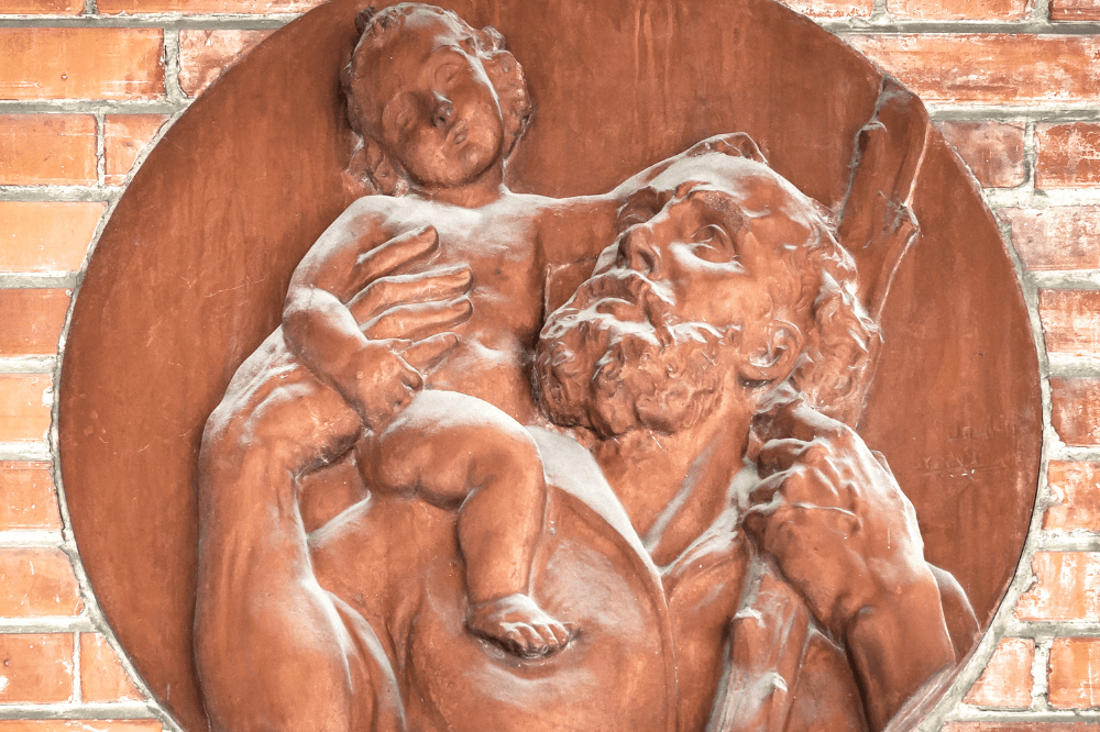 Terra cotta image of Joseph holding baby Jesus on his shoulder