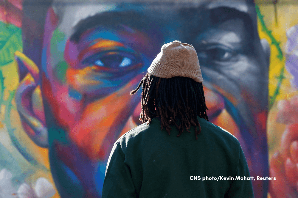 CNS photo by Kevin Mohatt, Reuters, person in front of mural of George Floyd