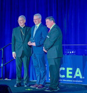 NCEA Board Chair Most Reverend Gregory J. Hartmayer, OFM Conv., Archbishop of Atlanta (L), Superintendent David Faber in the middle holding his award, and Steven Cheeseman, president/CEO of NCEA, on the right.