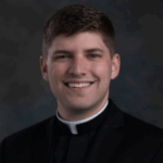 Photo of priest, Father Noah Thelen, smiling at the camera.